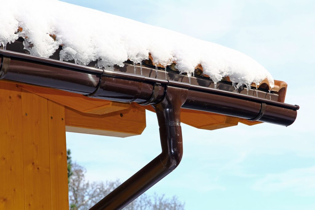 Wooden house with rain gutter in winter